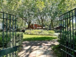 ein Tor zu einem Garten mit Bäumen und Gras in der Unterkunft Cosy studio flat on a budget in London