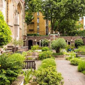 a garden with benches in front of a building at Cosy studio flat on a budget in London