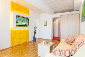 een woonkamer met een bank en een gele muur bij Joglland Hotel Prettenhofer in Wenigzell