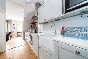 a kitchen with white cabinets and a sink at Stylish 3 BDR apartment wfree parking and garden in Kingston upon Thames