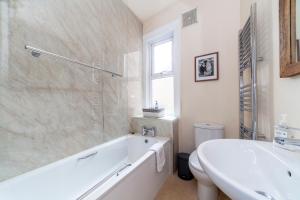 a white bathroom with a tub and a sink at Stylish 3 BDR apartment wfree parking and garden in Kingston upon Thames