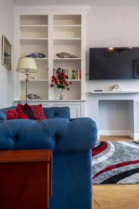 a living room with a blue couch and a tv at Stylish 3 BDR apartment wfree parking and garden in Kingston upon Thames +14 photos