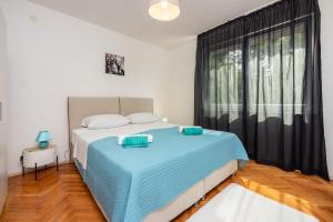 - une chambre avec un lit doté de draps bleus et une fenêtre dans l'établissement Apartment PAVLA, à Crikvenica