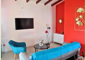 - un salon avec un canapé bleu et un mur rouge dans l'établissement Maison Bel'o Kado-Charme Créole, à Capesterre-Belle-Eau