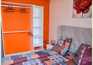 - une chambre avec des murs orange, un lit et un placard dans l'établissement Maison Bel'o Kado-Charme Créole, à Capesterre-Belle-Eau