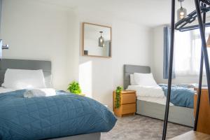 a bedroom with two beds and a mirror at Well-furnished 3-Bedroom house with Free Parking and Sky TV in Milton Keynes by HP Accommodation in Milton Keynes