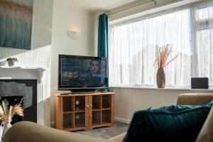 un salon avec une télévision et une cheminée dans l'établissement Well-furnished 3-Bedroom house with Free Parking and Sky TV in Milton Keynes by HP Accommodation, à Milton Keynes