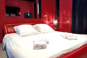 a red bedroom with a white bed with two towels on it at Appartement balnéo et sauna privés The Red Room in Mauguio +19 photos