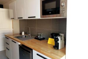 a kitchen with a sink and a microwave at Appartement balnéo et sauna privés The Red Room in Mauguio