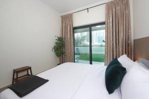 een slaapkamer met een wit bed en een groot raam bij Skyline Views 1 Bedroom Apartment Lake Facing in Dubai