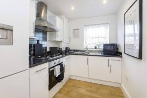 a white kitchen with white cabinets and a sink at York City Apartments in York