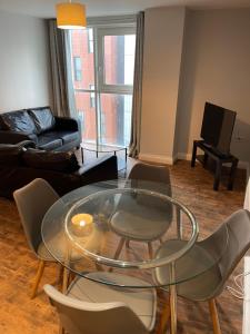 Belgrade Plaza Serviced Apartments في كوفينتري: غرفة معيشة مع طاولة وكراسي زجاجية