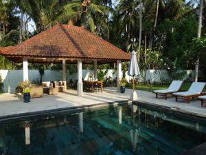 a pavilion with a table and a umbrella next to a pool at Villa Serenity in Candidasa