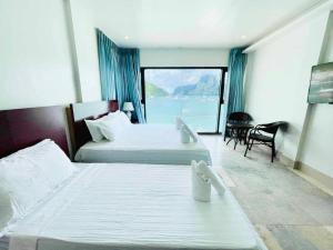 a hotel room with two beds and a large window at El Nido Beach Hotel in El Nido