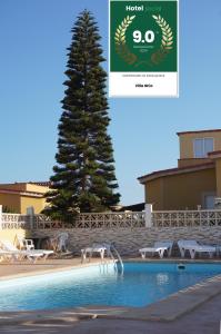 un albero accanto a una piscina con un albero di Villa Ghìo a Caleta De Fuste