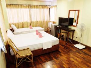 a bedroom with two beds and a desk and a television at El Nido Beach Hotel in El Nido