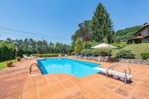 una piscina en un patio con sillas y sombrilla en Villa ai Boschetti, en Luciano