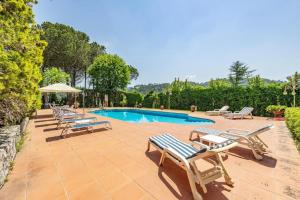 una piscina con tumbonas y una fila de sillas en Villa ai Boschetti, en Luciano