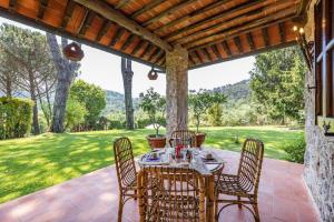 un patio con mesa y sillas en un porche en Villa ai Boschetti, en Luciano
