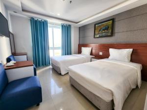 um quarto de hotel com duas camas e uma cadeira azul em FUSE Nha Trang em Nha Trang