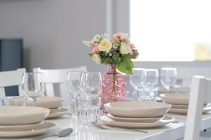a table with plates and glasses and a vase with flowers at Apartment with 2 Bedrooms and FREE GARAGE Poznań by Renters in Poznań