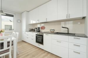 Apartment with 2 Bedrooms and FREE GARAGE Poznań by Renters في بوزنان: مطبخ بدولاب بيضاء ومغسلة وطاولة
