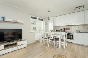 a kitchen with white cabinets and a table and chairs at Apartment with 2 Bedrooms and FREE GARAGE Poznań by Renters in Poznań
