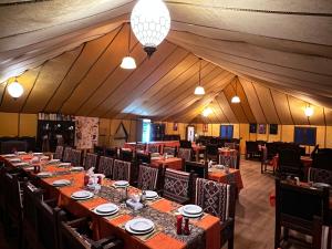 un gran comedor con mesas y sillas en una tienda de campaña en Luxury oasis camp en Merzouga