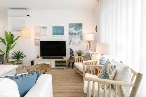 Una sala de estar con muebles blancos y un televisor de pantalla plana. en Consolação & Supertubos - Beach House II, en Atouguia da Baleia