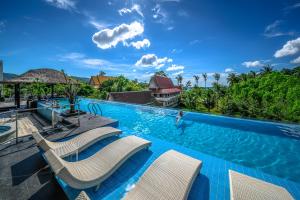 普吉岛-安达曼海滩海景度假酒店 Phuket-Andaman Beach Seaview Hotel في شاطيء باتونغ: مسبح مع كراسي وشخص في الماء