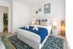 1 dormitorio blanco con 1 cama grande con sábanas y almohadas azules en Consolação & Supertubos - Beach House II, en Atouguia da Baleia 27 fotos más