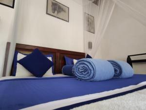 łóżko z niebieską pościelą i poduszkami w obiekcie Alone Cage Ella w mieście Ella