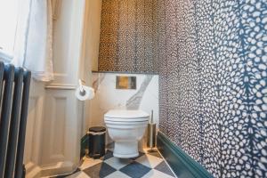 a bathroom with a toilet and a patterned wall at Hunton Park Hotel in Kings Langley