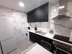 a kitchen with black cabinets and white marble walls at Aeropuerto - ifema - Wanda - Plenilunio in Madrid