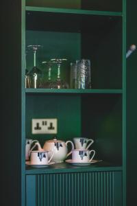a shelf with cups and saucers on it at Hunton Park Hotel in Kings Langley