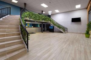 a lobby with a staircase with green plants at Days Inn by Wyndham Fort Pierce Midtown in Fort Pierce