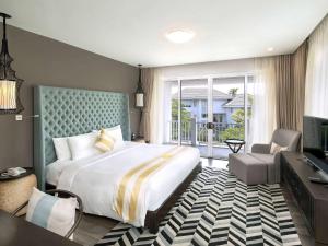 una camera d'albergo con un grande letto e una TV di Premier Village Danang Resort Managed By Accor a Da Nang