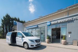 una furgoneta blanca estacionada frente a una tienda en Best Western Hotel München Airport en Erding