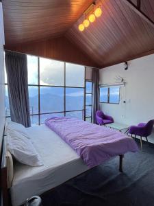 Un dormitorio con una cama grande con sábanas y ventanas púrpuras. en Nivriti Stays en Kanatal