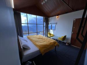 a bedroom with a bed with a yellow comforter at Nivriti Stays in Kanatal