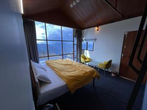 1 dormitorio con 1 cama con edredón amarillo en Nivriti Stays, en Kanatal