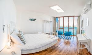 a white bedroom with a bed and a desk and a table at Umag center seafront seaview old town apartment rentistra 1 in Umag