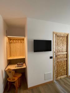 Habitación con mesa y TV en la pared. en AFFITTACAMERE ALLE ALPI, en Malborghetto Valbruna
