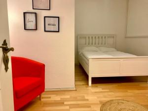 a bedroom with a bed and a red chair at Relax Aachener Boardinghouse Budget in Aachen