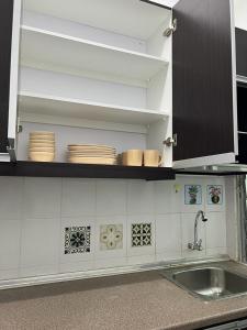 a kitchen with a sink and plates on a shelf at 162 RESIDENCY SELAYANG in Batu Caves