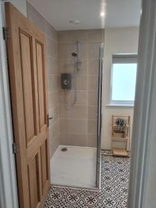 uma casa de banho com um chuveiro e uma porta de vidro em New spacious and sunny annexe with Underfloor heating throughout em Culmstock