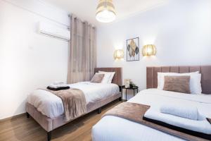 two beds in a bedroom with white walls and wood floors at Quattro Beachfront Sea View Ap 206 in Larnaka