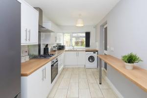 a kitchen with white cabinets and a washer and dryer at 2 Bed Littleover Derby House (long stays / parking) in Derby