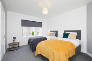 a white bedroom with two beds and a window at 2 Bed Littleover Derby House (long stays / parking) in Derby