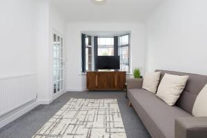 a living room with a couch and a tv at 2 Bed Littleover Derby House (long stays / parking) in Derby